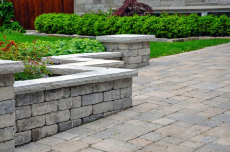 A seat wall with pillars and natural stone coping helps define a A seat wall with pillars and natural stone coping helps define a